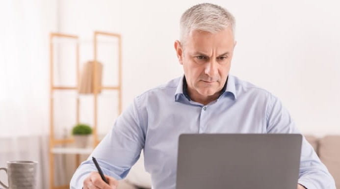 Older man with silver hair working at laptop