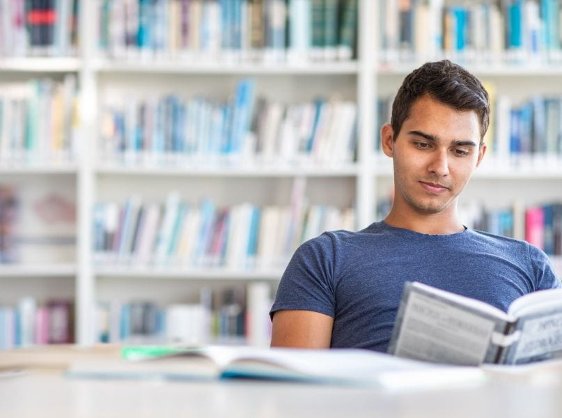 Young man reading in library for leisure