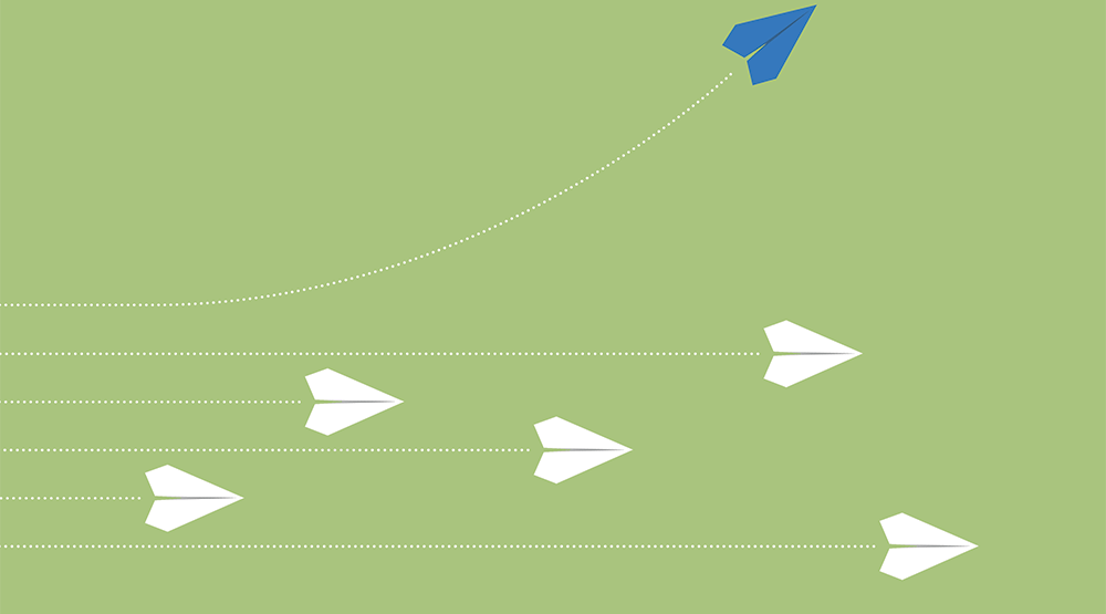 5 white paper aeroplanes in flight, and one blue one peeling off upwards. 