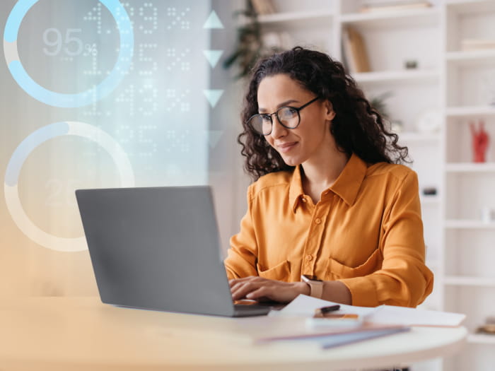 Woman in orange shirt typing on laptop