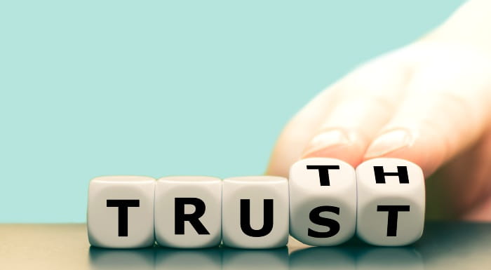 Lettered blocks spelling 'trust' with the last two blocks being turned by a hand so the blocks spell 'truth' instead