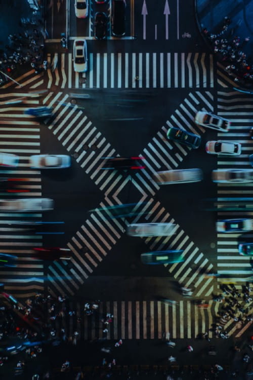 Blurred cars on a busy cross roads at night. 