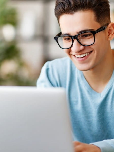 Young man wearing glasses looking at laptop screen
