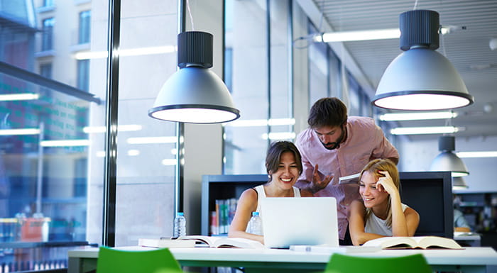 Three people around a laptop in an office
