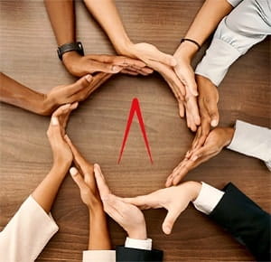 Several hands arranged in a circle on a wooden surface, with palms and fingers touching to form a unified shape, symbolizing teamwork, unity, and collaboration.