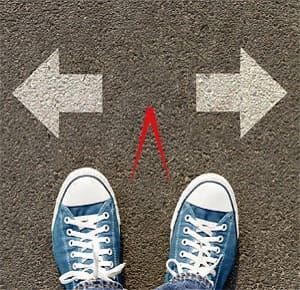 A pair of blue sneakers on asphalt, positioned between two large white arrows painted on the ground, one pointing left and the other pointing right, symbolizing a choice or decision point.