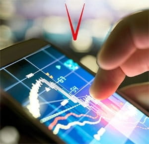A close-up of a hand interacting with a smartphone screen displaying colourful financial charts and graphs, against a blurred background of lights. The image suggests data analysis or stock market tracking.