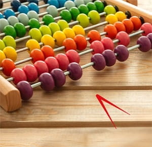 A colourful wooden abacus placed on a wooden surface, featuring multiple rows of beads in vibrant colours used for counting or basic arithmetic.