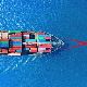 A cargo ship sailing on deep blue water, viewed from above. The vessel is loaded with colourful shipping containers arranged in neat rows, creating a striking contrast against the surrounding ocean.