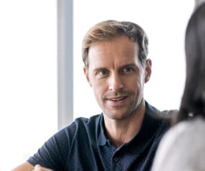 Man in black top talking to colleague
