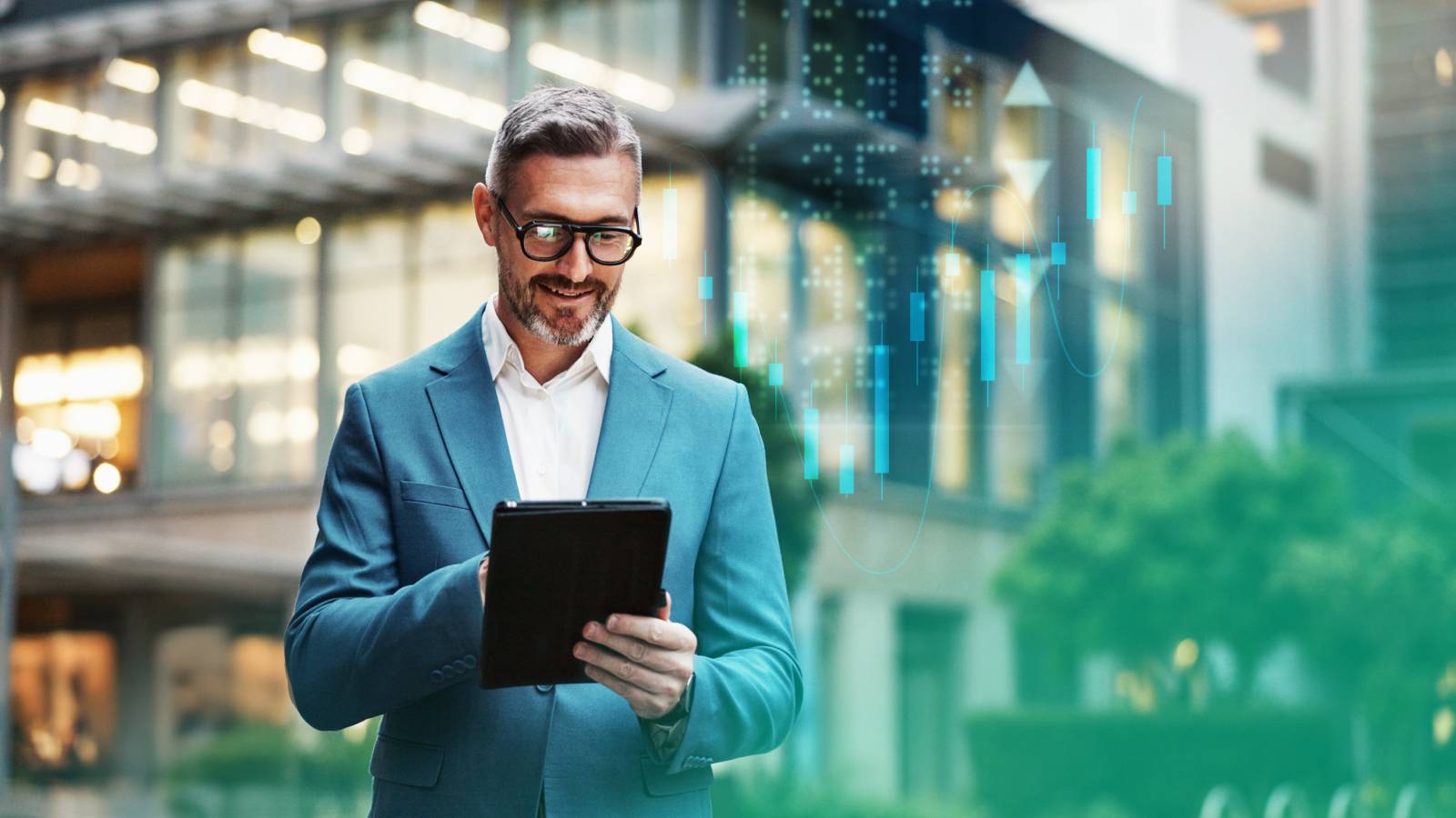 A person in a blue suit stands outdoors in an urban setting, focused on using a digital tablet.