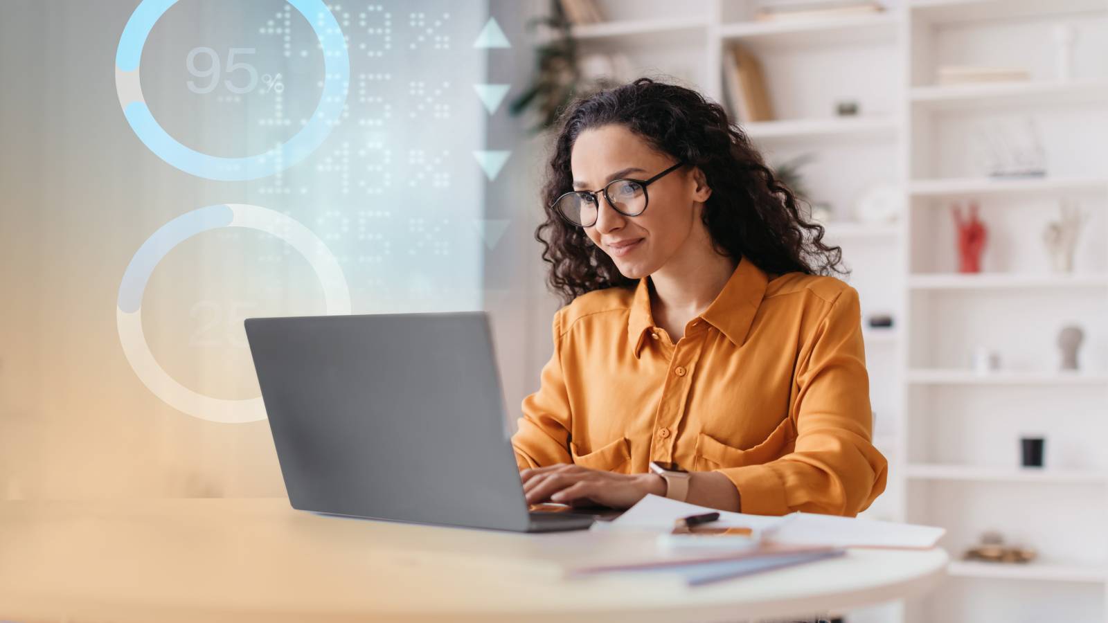 A person sits at a desk working on a laptop in a bright office space.