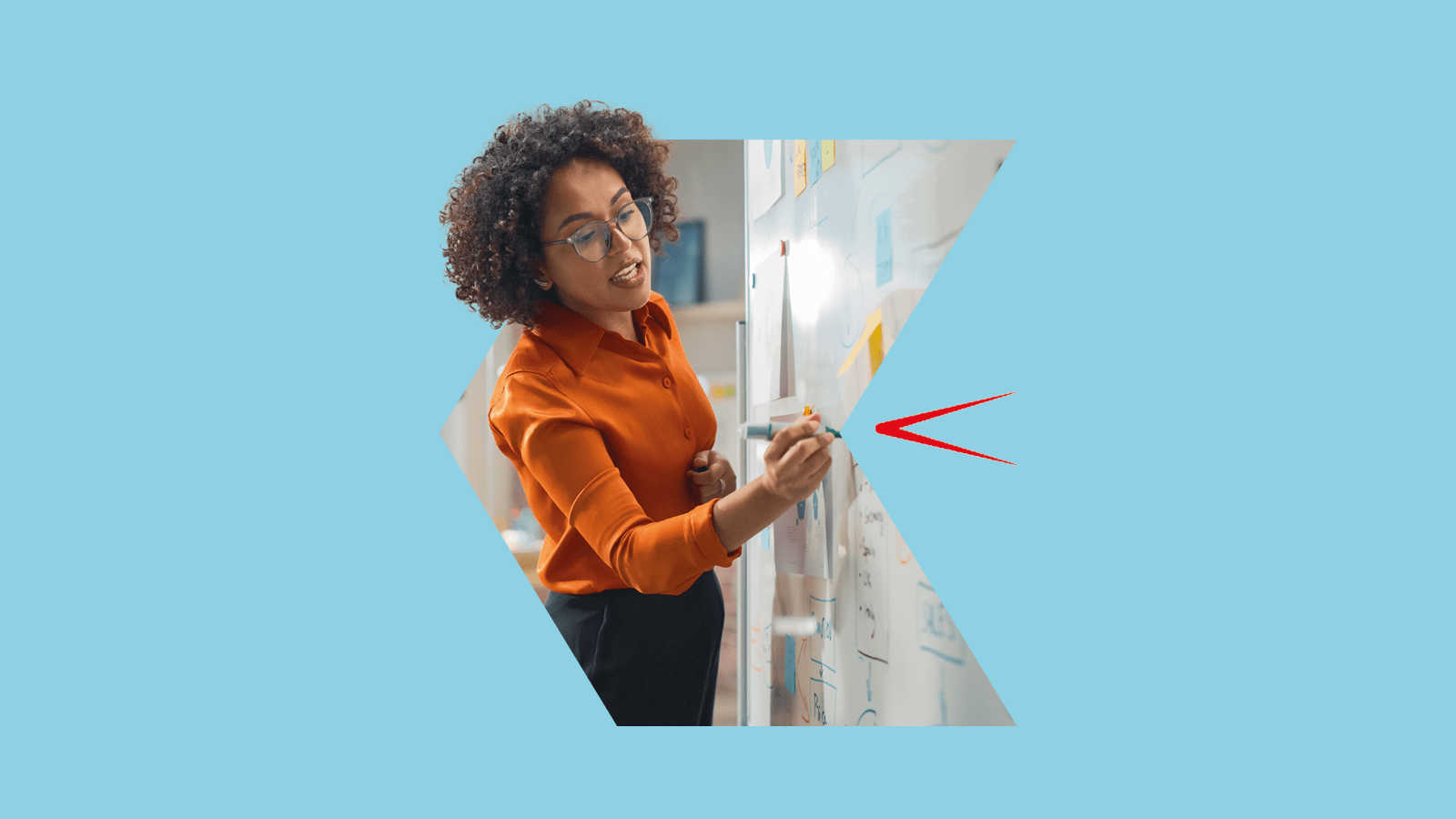 Woman in an orange shirt writing on a whiteboard against a blue background