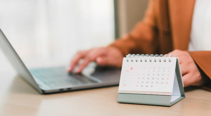 Person using laptop with a calendar in front