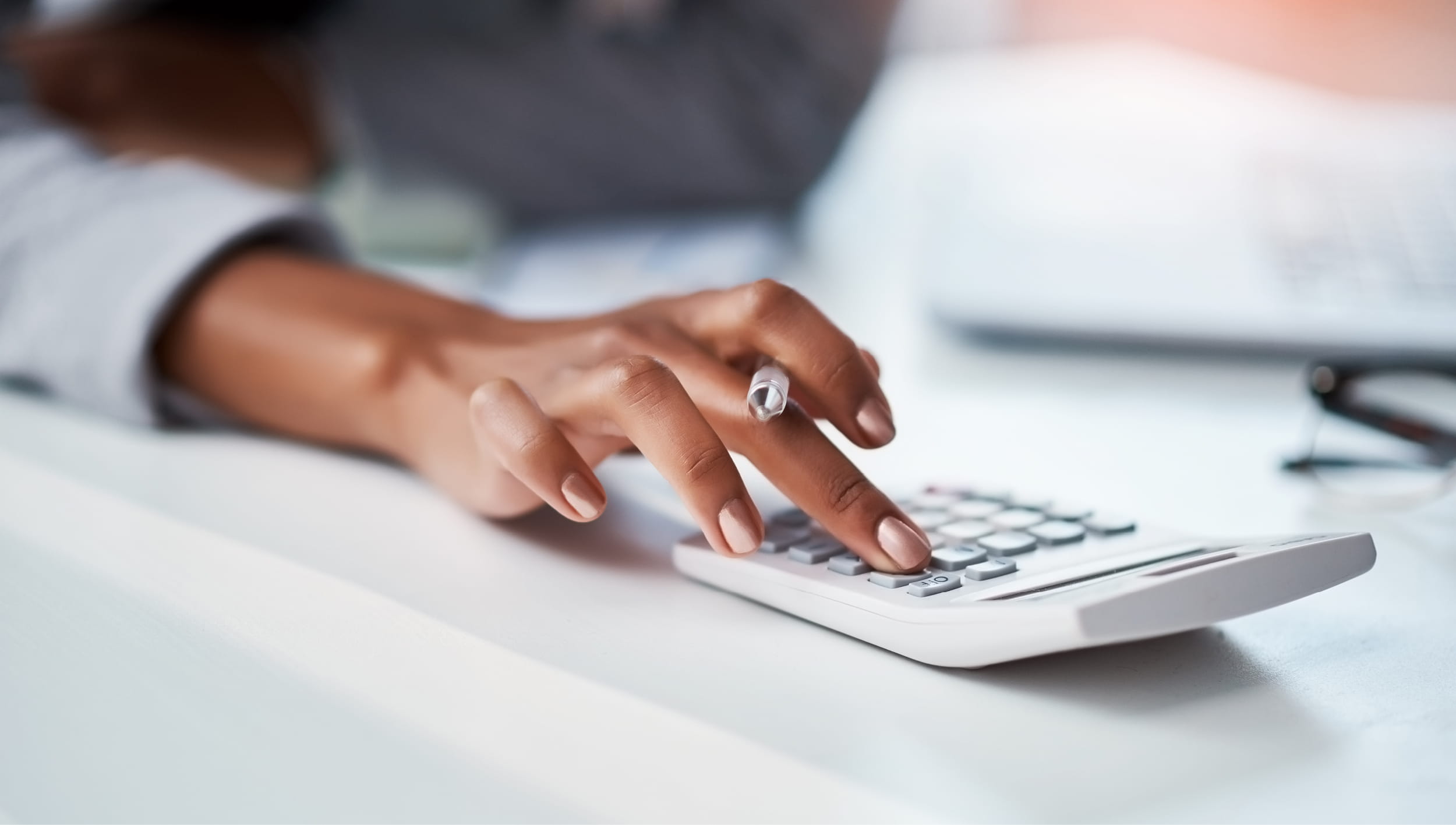A person's hand typing into a calculator