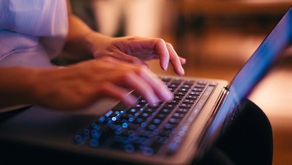 An photograph of hands typing on a laptop keyboard