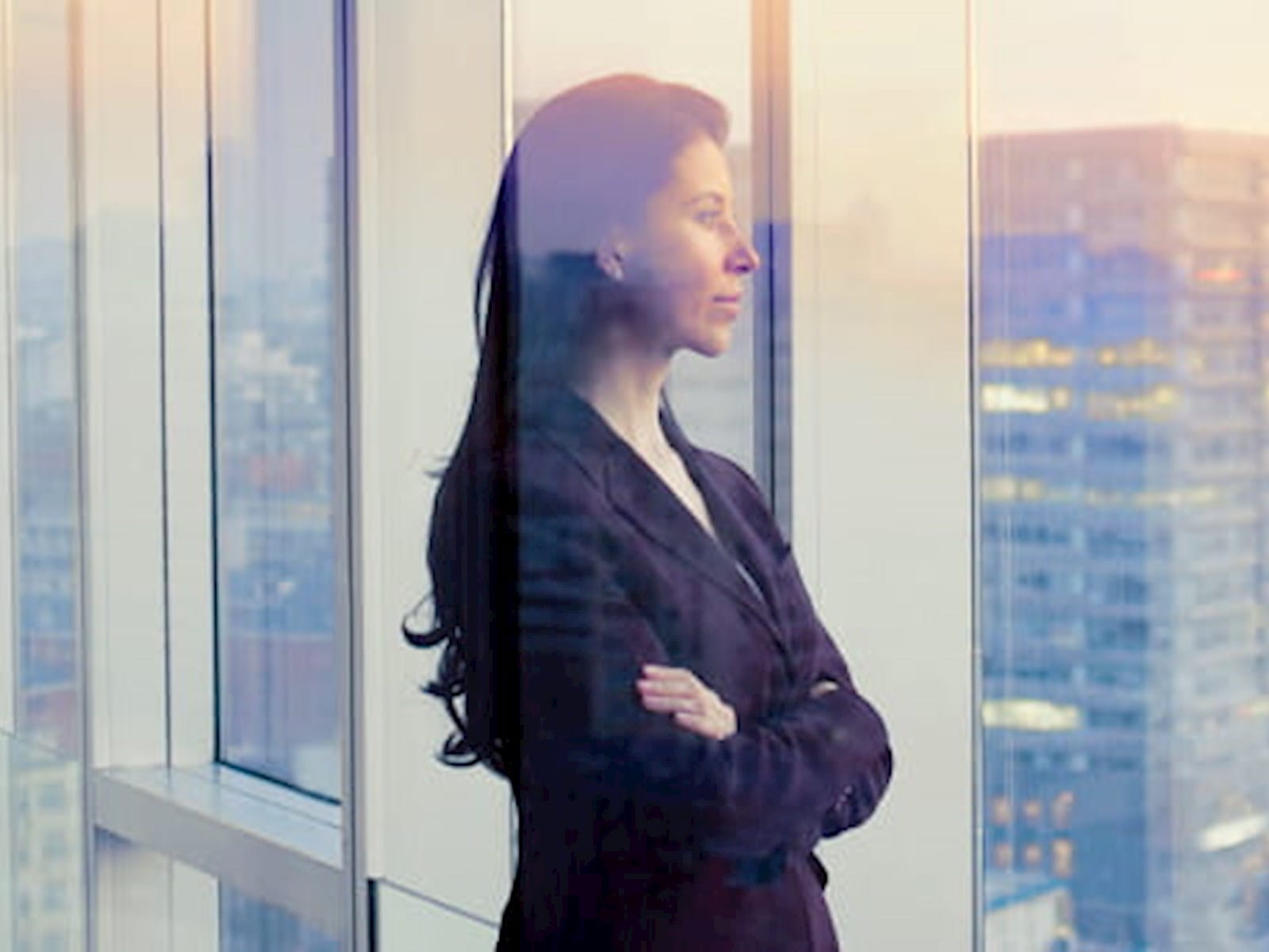 An office worker staring out of an office window over a city