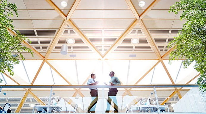 Two people standing on a gallery in an office building.