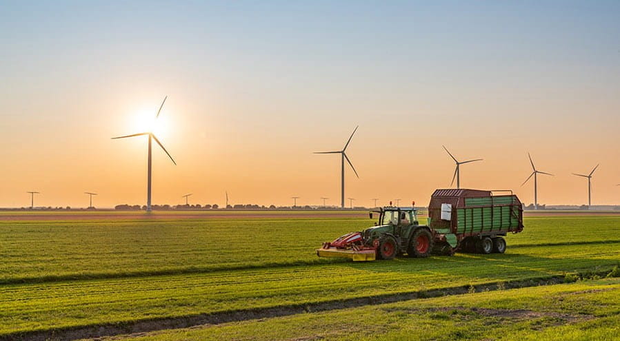 A tractor in a field with wind turbines in the distance