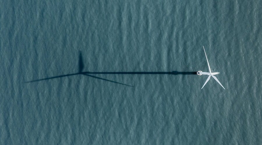 A wind turbine casting a long shadow on the sea