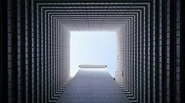 View from the bottom of a lightwell in a building, looking up towards sky