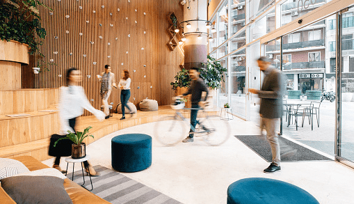An office lobby with blurred figures milling inside it 