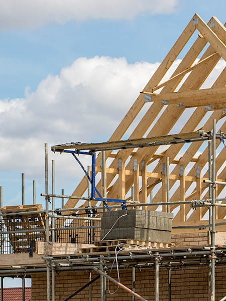 Timber framework of house roof trusses with scaffold.