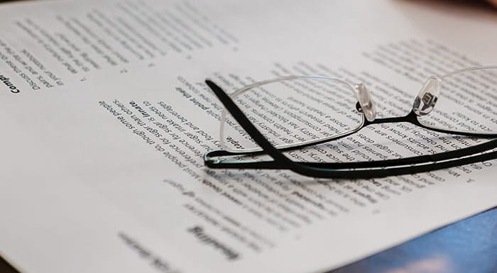 Report papers on a desk with a pair of glasses on them.