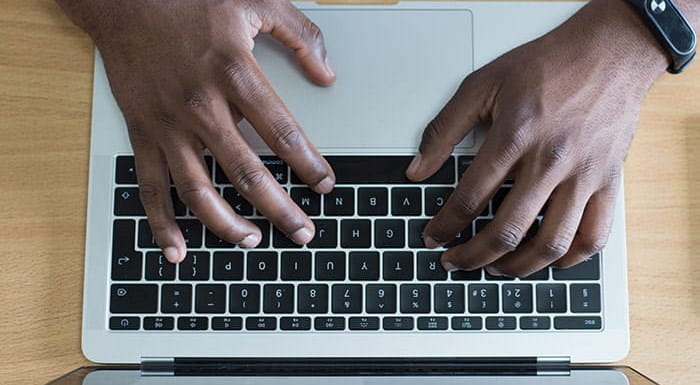 A pair of hands typing at a laptop.