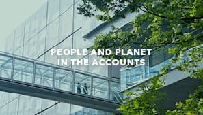A modern glass office building, two people and a leafy tree
