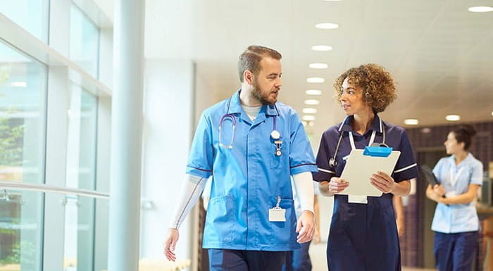 Two medical professionals walking and talking in a hospital corridor