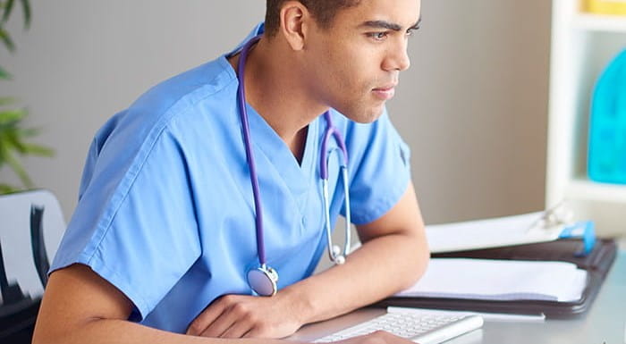 A medical professional sitting at a desk using a computer mouse