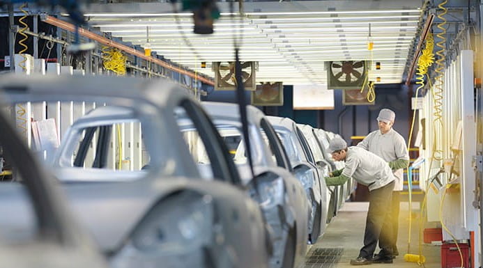 Cars on an assembly line with two people working on them