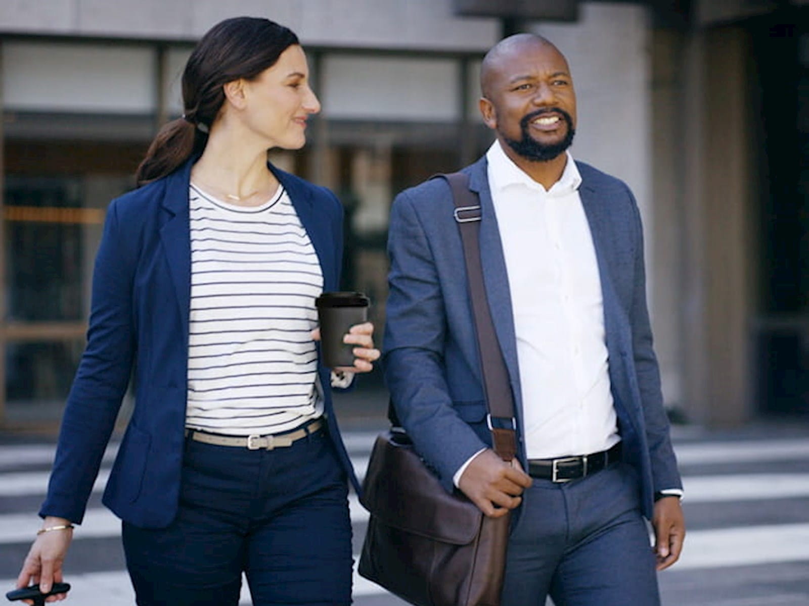 Two people in business attire walking outside together
