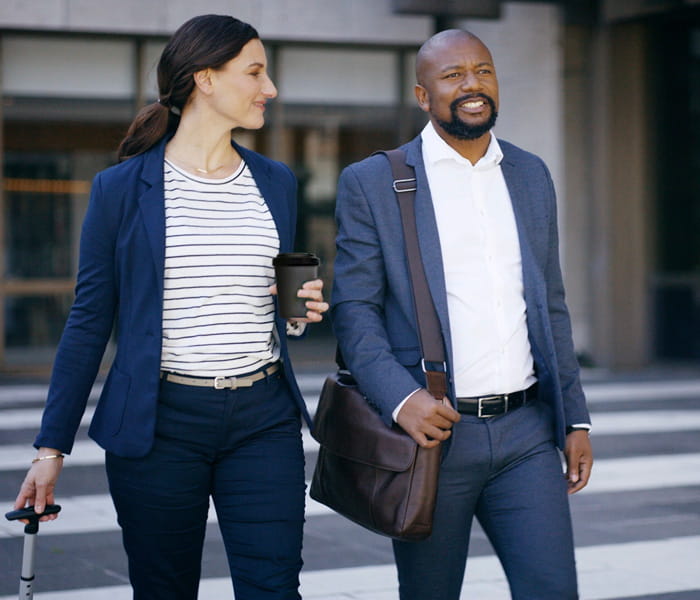 Two people in business attire walking outside together