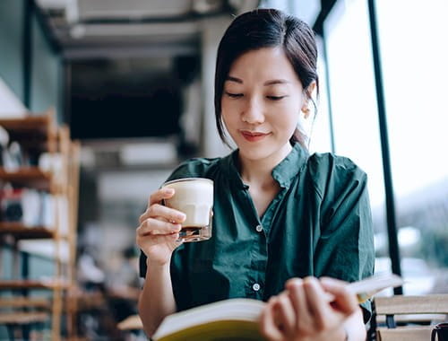 young asian woman green shirt studying book reading office study room cup of coffee