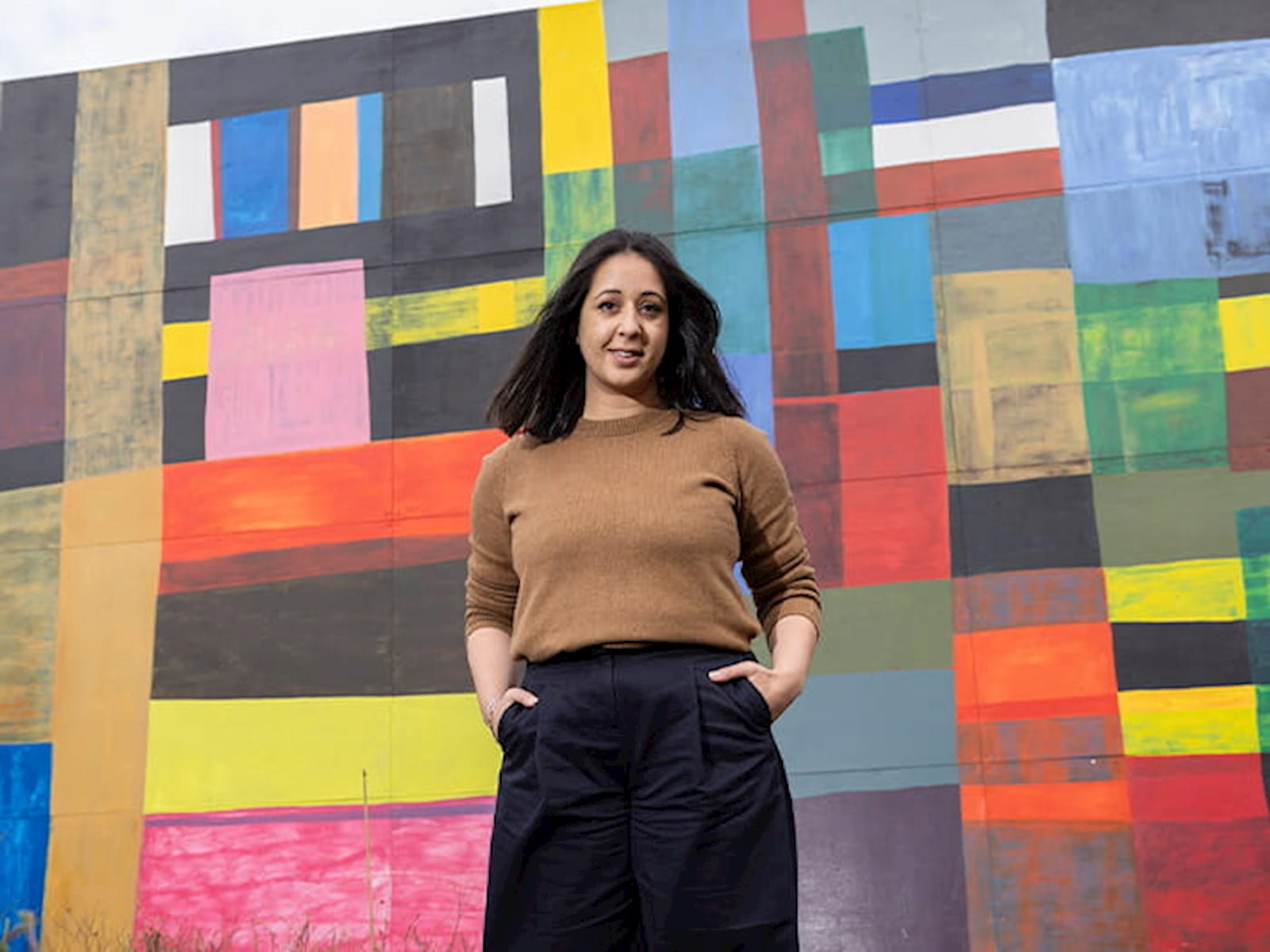 Alina Cummins, Head of Finance at Serpentine, young woman standing in front of wall mural colourful