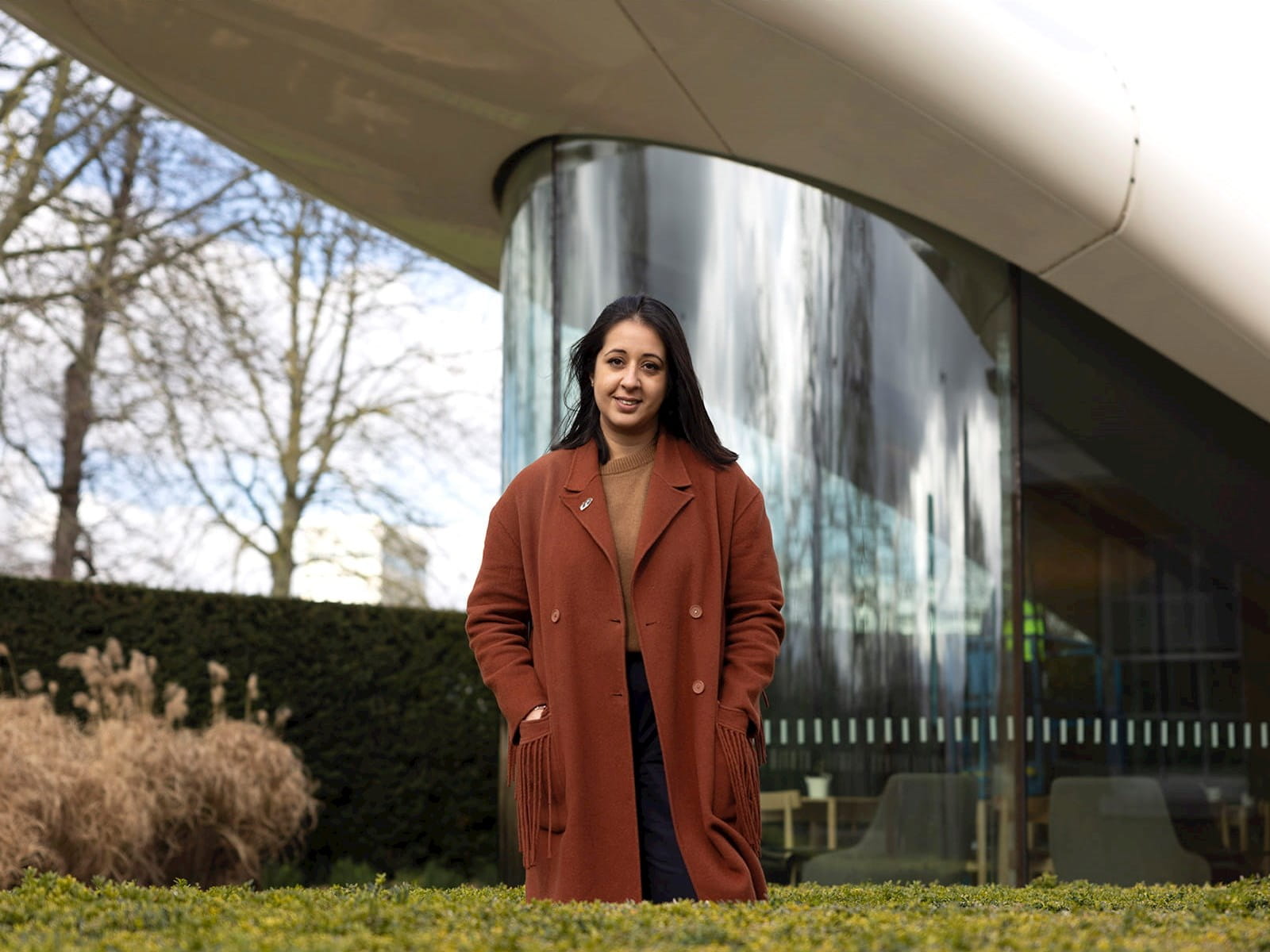 Alina Cummins, Head of Finance at Serpentine, young woman standing in front of modern glass building plants trees