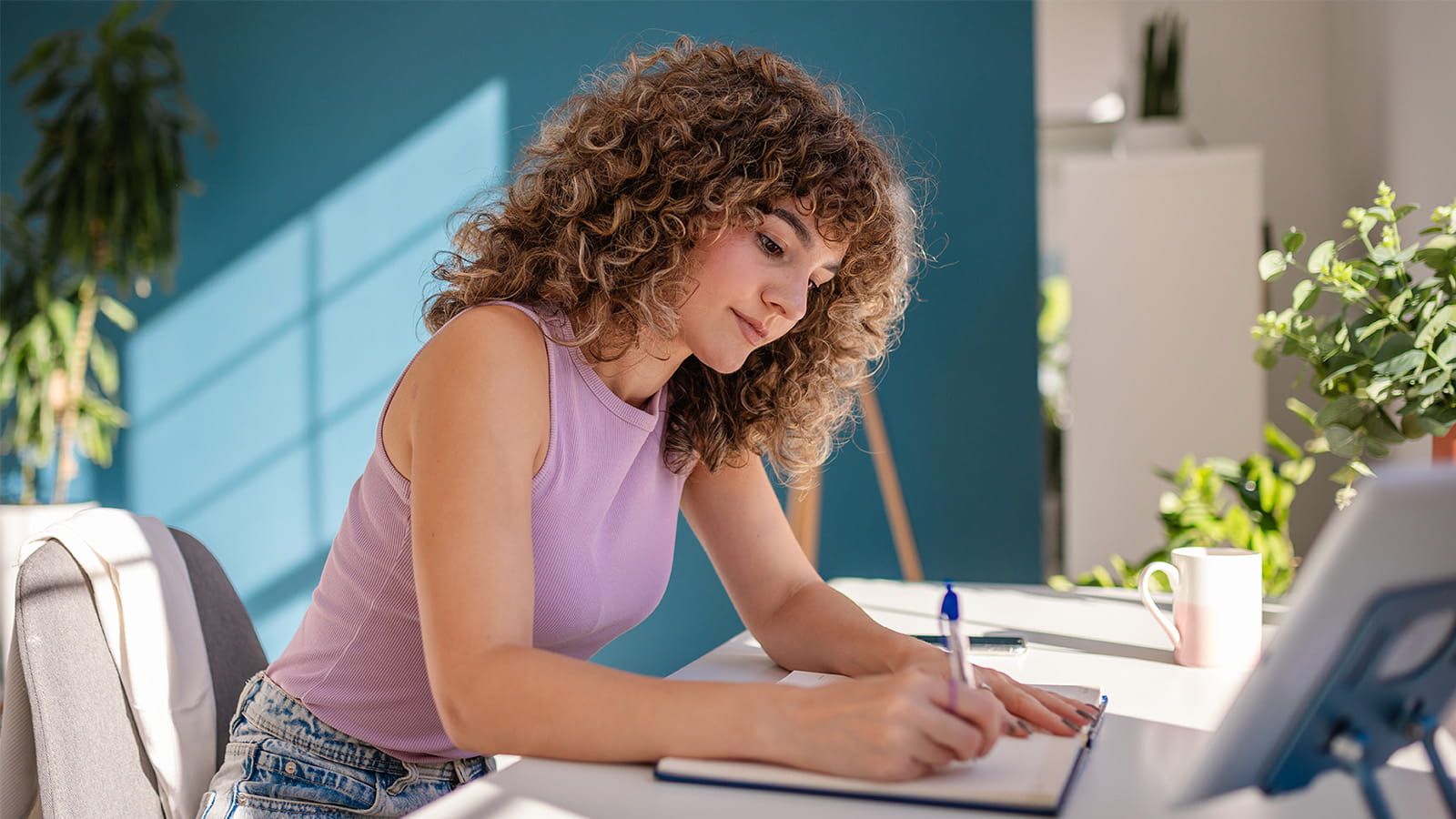 young woman student working studying in a home office writing pen paper desk