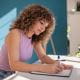 young woman student working studying in a home office writing pen paper desk