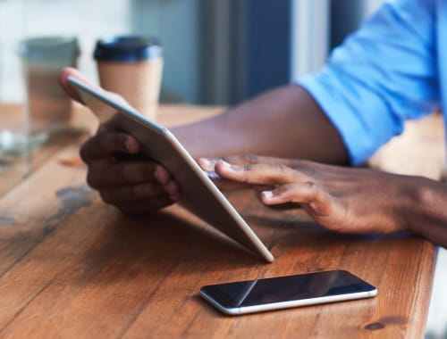 Male on his tablet with his phone nearby in a cafe