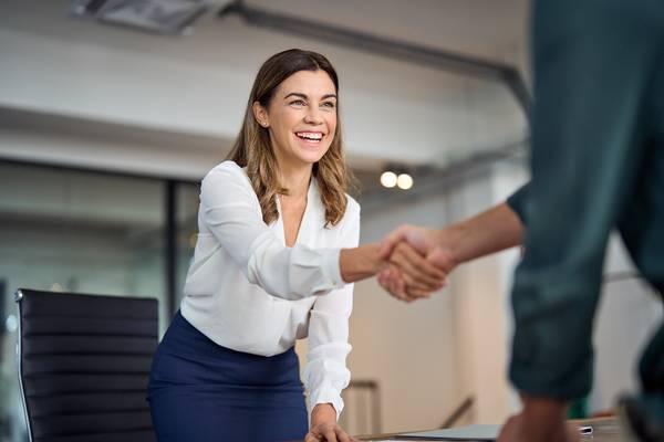 businesswoman shaking hands across a desk