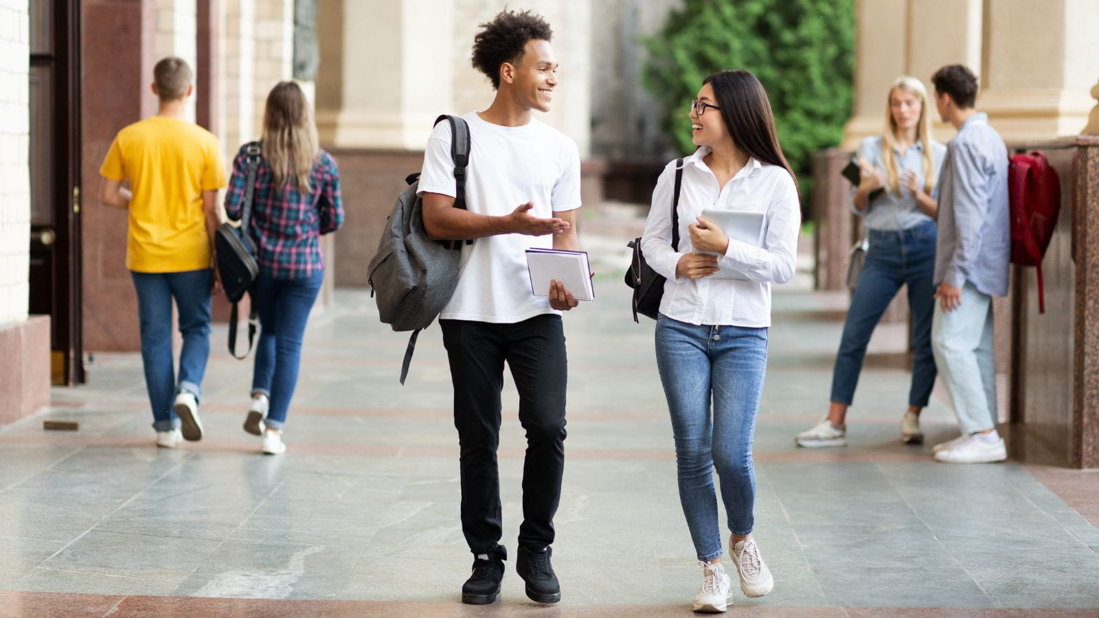 diverse classmates chatting walking after class university campus outdoors