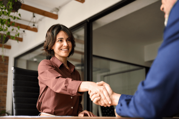 young businesswoman shaking hands with a colleague across a desk