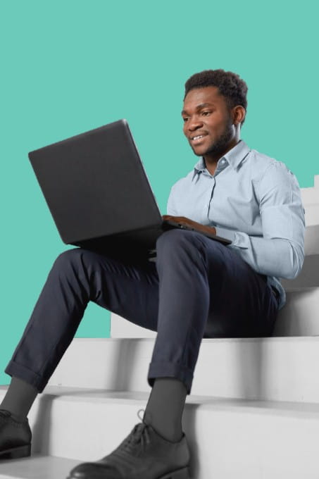 Image of a man sat on stairs working on a laptop