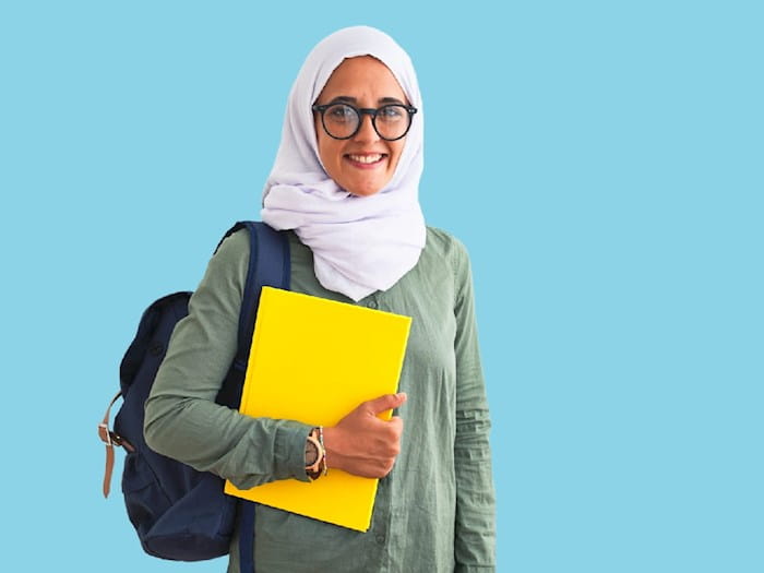 Female student in headscarf holding a yellow folder