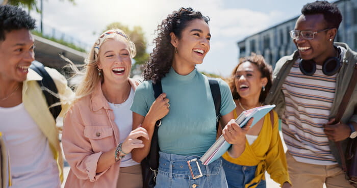 A diverse group of university students walking together in a row. They are laughing and smiling.