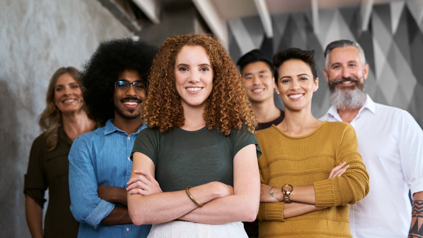 Diverse group of smiling colleagues stood up and looking into the camera.