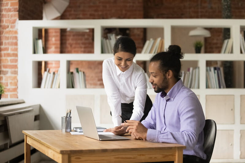 Smiling Indian businesswoman mentor training African American intern in office
