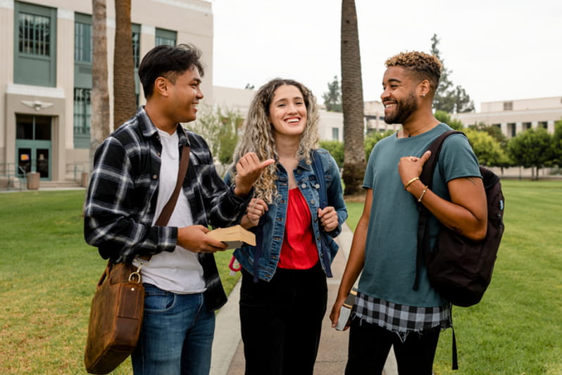 Students speaking with books and laptop